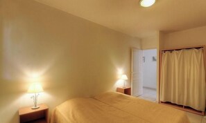 Ein Hotelzimmer mit einem Bett, zwei Nachttischlampen, einer Tür und einem Vorhang.