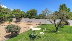 Un jardin avec une table et des chaises, un hamac et un petit espace aménagé en jardin.
