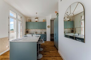 Eine moderne Küche mit einer Marmorinsel, Türkis-Blau-Schränken und einem großen Spiegel.