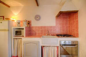 A compact kitchen with a refrigerator, stove, sink, and a clock on the wall. - Petirossu - CAGNANO - Guest house (CAGNANO)