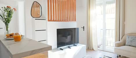 A modern living space with a kitchen area, a dining table, a sofa, and a fireplace.