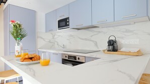 Eine moderne Küche mit hellblauen Schränken, einer Marmorarbeitsplatte, einem eingebauten Ofen und einem Wasserkocher auf der Theke.