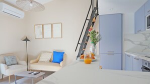 Ein modernes Wohnzimmer mit Sofa, Couchtisch und Küchenbereich mit Schränken und Kühlschrank.