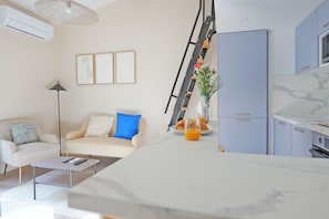 A modern living room with a sofa, coffee table, and a kitchen area with cabinets and a refrigerator. - Appartement avec Rooftop à Montpellier - Welkeys (Montpellier)