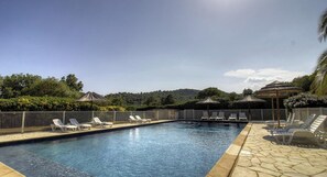 A swimming pool with lounge chairs and umbrellas, surrounded by a fence and greenery. - 10673 - SAINTE LUCIE DE PORTO VECCHIO (SAINTE LUCIE DE PORTO VECCHIO)