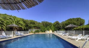 A swimming pool with lounge chairs and umbrellas, surrounded by greenery. - 10673 - SAINTE LUCIE DE PORTO VECCHIO (SAINTE LUCIE DE PORTO VECCHIO)