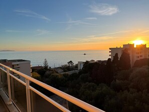 Ein Küstenblick mit Sonnenuntergang, Gebäuden und wolkenlosem Himmel.