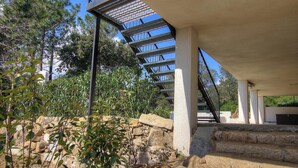 A staircase with metal railings leading to a covered area, surrounded by stone walls and greenery. - Villa Rossa - SARI SOLENZARA (SARI SOLENZARA)