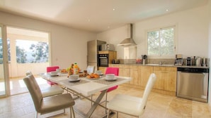 A modern kitchen with a dining area, large windows, and a view of the outdoors. - Villa Rossa - SARI SOLENZARA (SARI SOLENZARA)
