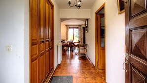 Un corridoio con porte in legno, una sala da pranzo con tavolo e sedie, e un lampadario.