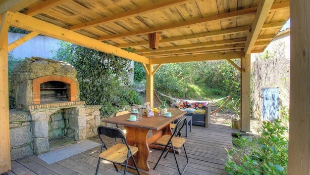 An outdoor patio with a stone-built oven, wooden deck, and a table with chairs. - U Castagnu - CANNELLE D'ORCINO (CANNELLE D'ORCINO)