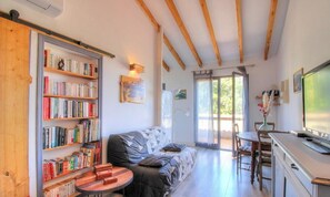 Ein gemütliches Wohnzimmer mit Sofa, Couchtisch, Bücherregal, Esstisch und Fernseher.