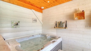 Un soffitto in legno, una vasca idromassaggio e uno scaffale con oggetti decorativi.