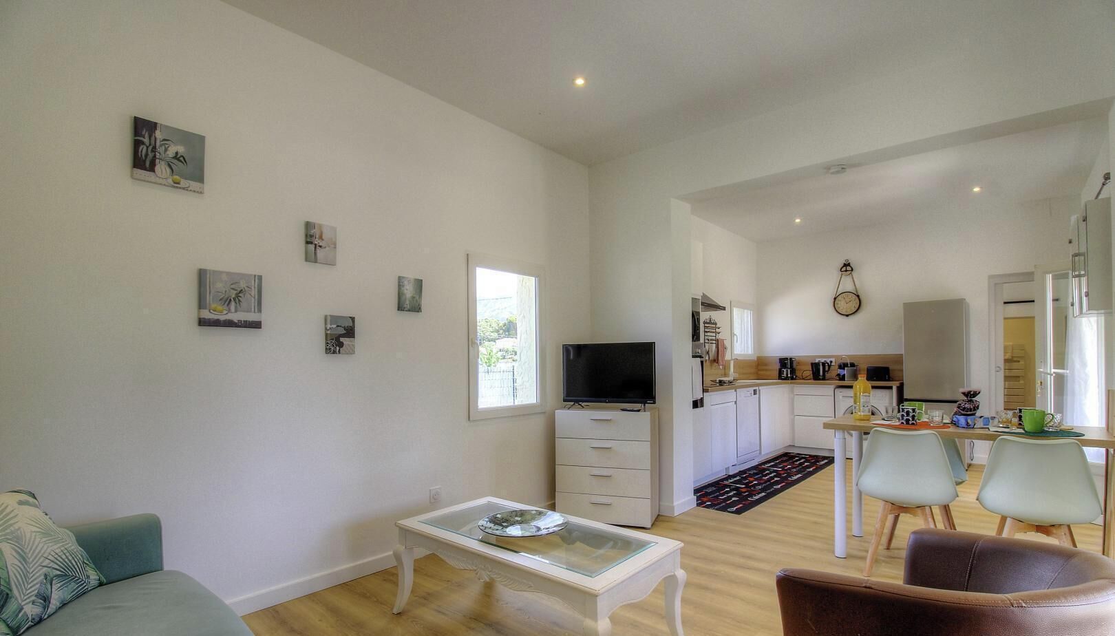 Un espacio habitable compacto con sofá, televisor, zona de comedor y cocina.