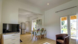Una cucina moderna con TV, frigorifero e zona pranzo con sedie e tavolo.