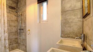 Une salle de bain avec une douche, des toilettes et deux lavabos.