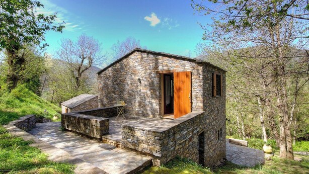A stone building with a wooden door, a small outdoor seating area, and a stone pathway leading to it. - Petrera 1 - CASABIANCA (CASABIANCA)