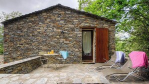 A stone cottage with a wooden door, a small table with bottles, and two lounge chairs with blankets. - Petrera 1 - CASABIANCA (CASABIANCA)