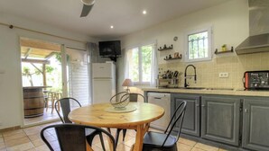 Een keuken met een eettafel, stoelen, een televisie en een koelkast.