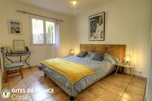 Ein Schlafzimmer mit einem Bett, Nachttischen, einem Fenster, einem Schreibtisch mit Büchern und einem Poster an der Wand.