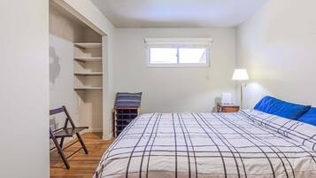 Ein Schlafzimmer mit Bett, Fenster, Stuhl, Lampe und Regalelement.