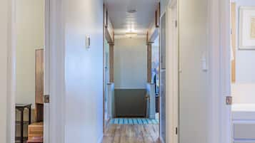 A hallway with wooden flooring, white walls, and a ceiling light fixture.