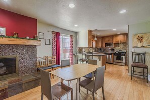 Een moderne keuken met houten kastjes, een inbouwoven en een eethoek met een tafel en stoelen.