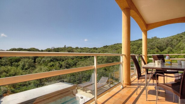 Un balcone con piscina, mobili da esterno e una vista panoramica su un pendio boscoso.