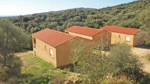 Un edificio con tetto in tegole rosse, circondato da vegetazione e colline.