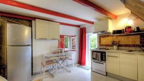 Una cocina compacta con refrigerador, estufa y comedor.