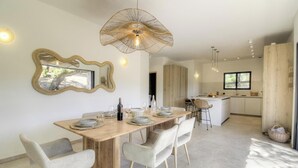 Une cuisine moderne avec un îlot central, un coin repas doté d’une table et de chaises en bois, et un grand miroir au mur.