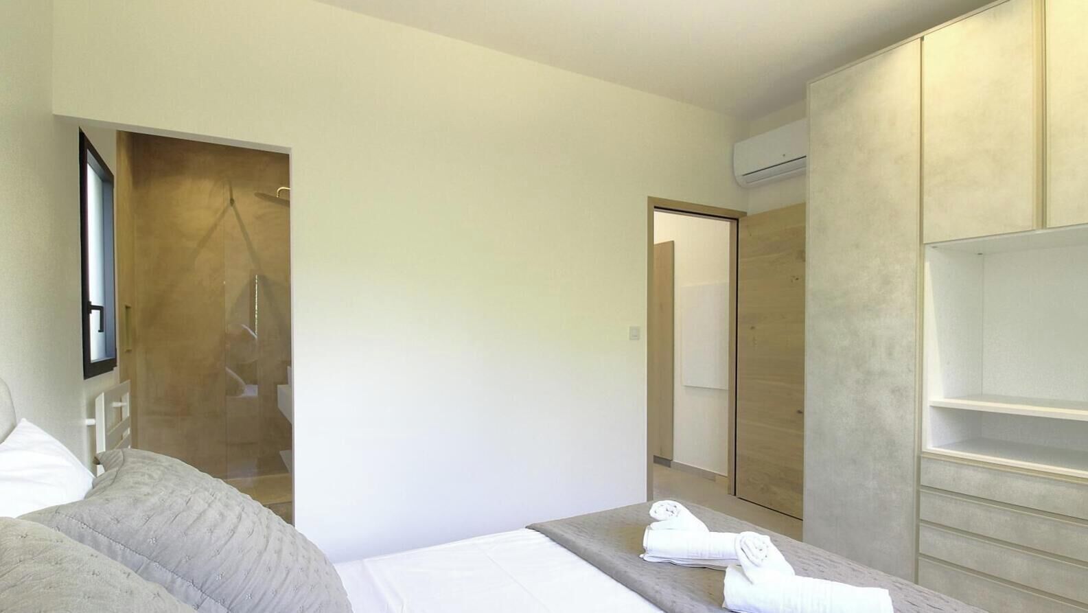 Een hotelkamer met een bed, een douche, een kledingkast en een spiegel.