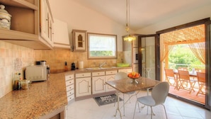 A kitchen with a dining area, a window, and a view of the outdoors. - A Parniccia - PORTO VECCHIO (PORTO VECCHIO)