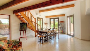 A spacious living area with a wooden staircase, a dining table, and a bookshelf. - A Parniccia - PORTO VECCHIO (PORTO VECCHIO)