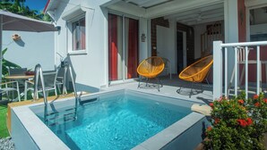 En pool med en kant av glas, en stege och två fåtöljer i rotting.