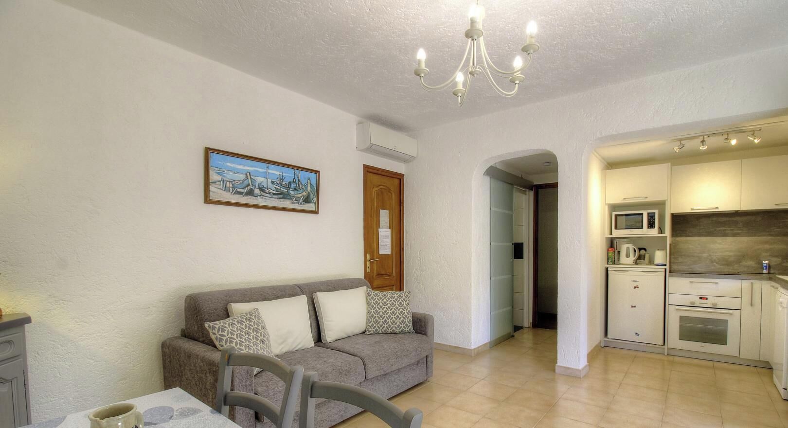 Una sala de estar con sofá, una mesa de comedor y una cocina con microondas y horno.