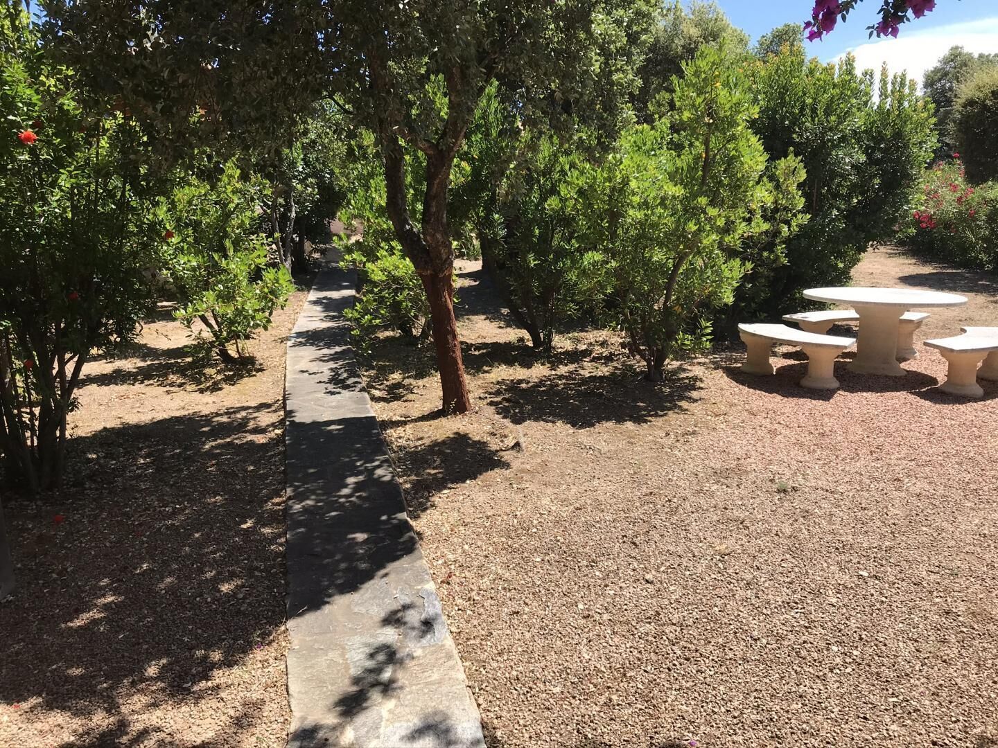 Un vialetto nel giardino conduce a un'area salotto esterna con tavoli e sedie.