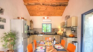 A kitchen with wooden ceiling, a dining table with orange chairs, and a refrigerator. - Pastricciola - LEVIE (LEVIE)