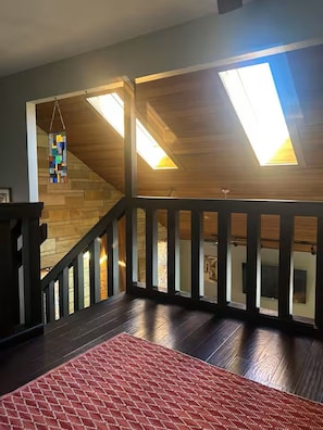 A wooden staircase with a railing, a skylight, and a hanging stained glass piece. -                                                        Star Water Getaway (Mary Esther)