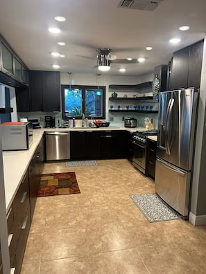 A modern kitchen with stainless steel appliances, dark cabinetry, and a window providing natural light. -                                                        Star Water Getaway (Mary Esther)