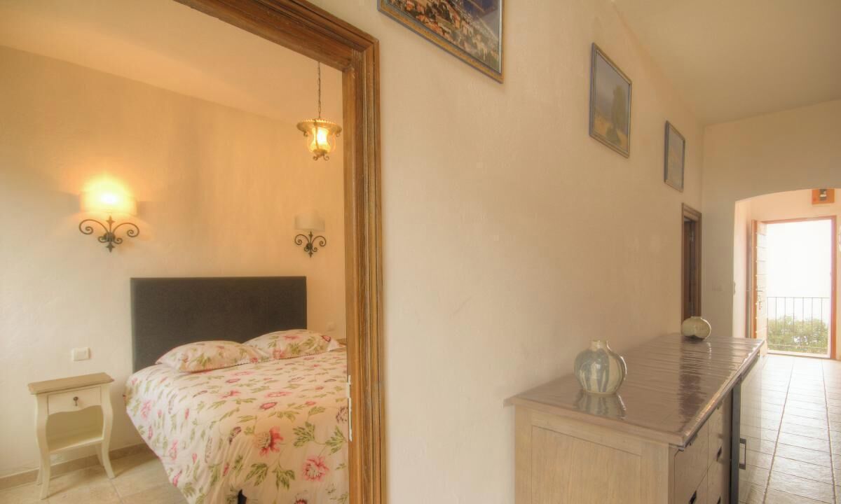 A bedroom with a bed, bedside lamps, a nightstand, a dresser, and a painting on the wall.