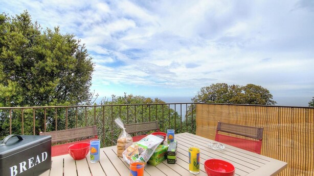 Ein Tisch im Freien mit Speisen, einem Grill und Blick aufs Meer.