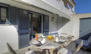 Eine Terrasse im Freien mit einem runden Esstisch und Stühlen darum herum.