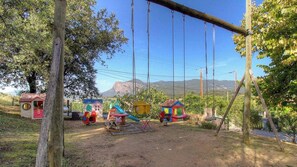 Une aire de jeux avec des balançoires, des toboggans et de petites cabanes.