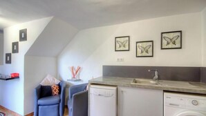 A compact kitchen with a dishwasher, a sink, and a washing machine. There are framed butterfly pictures on the wall.