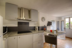 Eine moderne Küche mit Einbauherd, Mikrowelle und Kaffeemaschine auf der Arbeitsfläche.