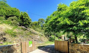 A gated entrance with a wooden fence, a stone wall, and a small building with a green door. - Ortu di Casa - MURATO (MURATO)