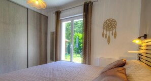 A bedroom with a bed, curtains, a dreamcatcher, and a view of greenery outside. - U Castellu di Garanza (SAN DAMIANO)