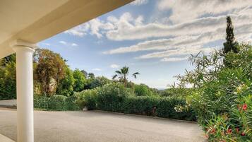 Un'area di parcheggio coperta con vista su un giardino curato e un cielo sereno.