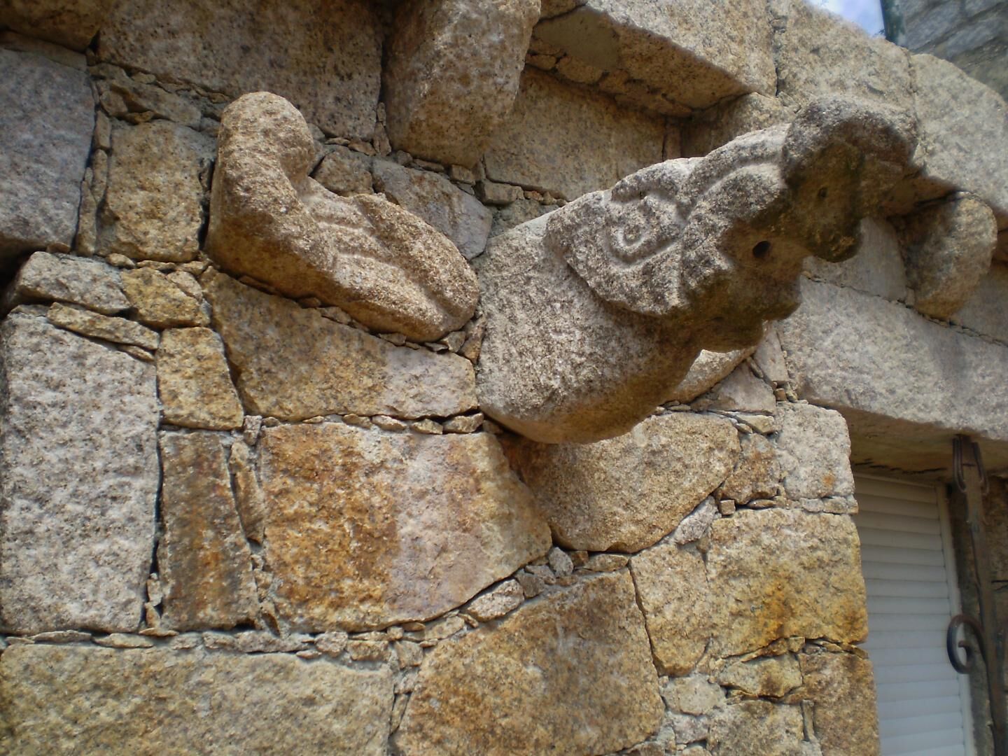 A stone wall with a carved animal figure.